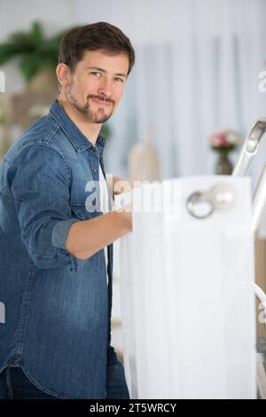 young man installing curtains over window Stock Photo