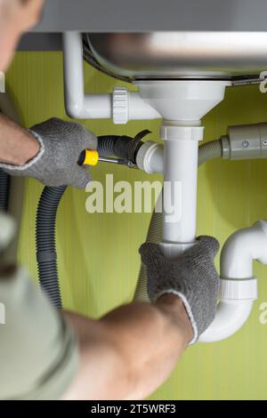 Repairing a pipe in the kitchen under the sink. kitchen plumbing repairs. connecting the washing machine drain. fix water plumbing leaks, replace the Stock Photo