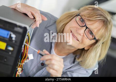 mature woman using screw driver fix pc Stock Photo