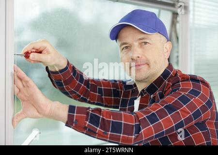 worker fasten the handle to a plastic window Stock Photo