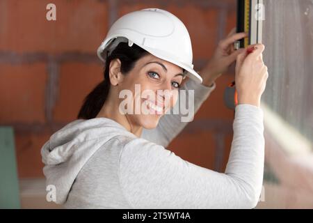 woman measuring window frame in construction site Stock Photo