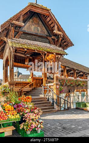Market stands in front of the Chapel Bridge (Kapellbrücke) at the waterfront of the River Reuss in Lucerne, Switzerland. Stock Photo