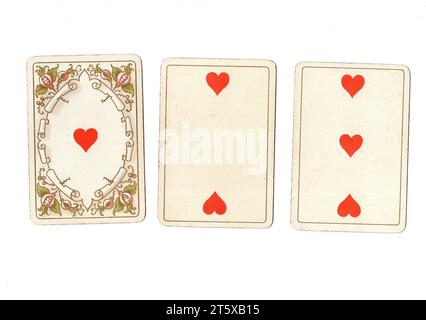 Three antique playing cards showing an ace, two and three of hearts on a white background. Stock Photo