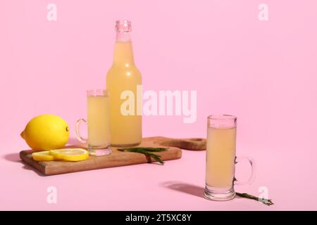 Wooden board with bottle and shots of tasty Limoncello on pink background Stock Photo