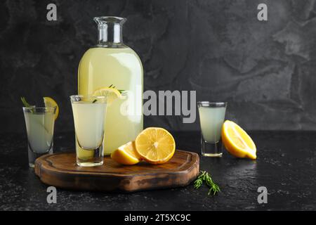 Bottle and shots of tasty Limoncello with rosemary on black background Stock Photo