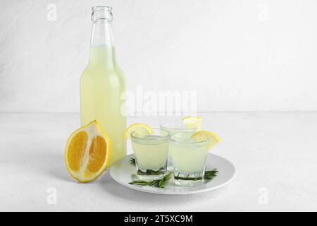 Bottle and shots of tasty Limoncello with rosemary on white table Stock Photo