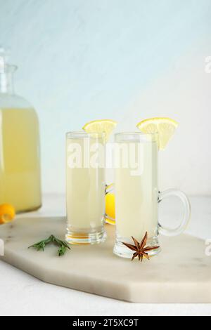 Board with shots and bottle of tasty Limoncello on white background Stock Photo