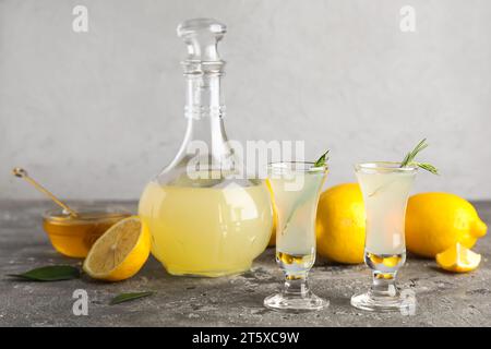 Shots and bottle of tasty Limoncello with rosemary on grey table Stock Photo