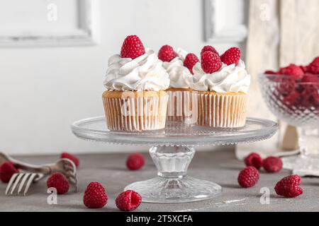 Stand with tasty raspberry cupcakes on table Stock Photo