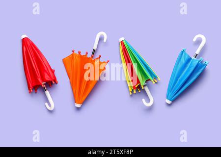 Mini stylish umbrellas on lilac background Stock Photo