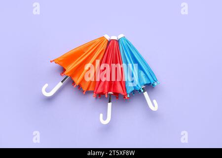 Mini stylish umbrellas on lilac background Stock Photo
