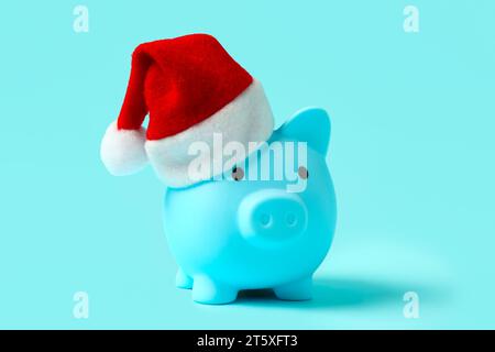 Piggy bank with Santa hat on blue background Stock Photo