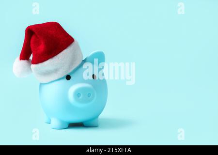 Piggy bank with Santa hat on blue background Stock Photo