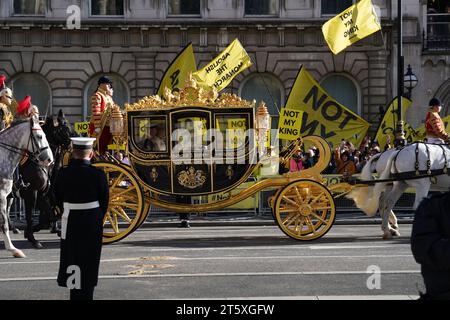 The carriage carrying King Charles III and Queen Camilla passes by protesters from anti-monarchy pressure group Republic as they demonstrate outside the Palace of Westminster in London during the State Opening of Parliament in the House of Lords. Picture date: Tuesday November 7, 2023. Stock Photo