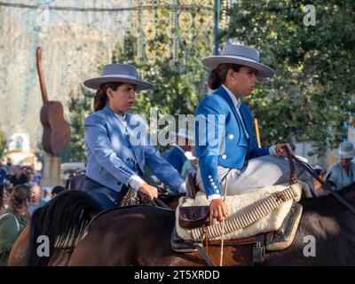 Groups of horse riders dressed in typical Andalusian costume, riding through the fairgrounds of Fuengirola during the celebration of the Feria Stock Photo