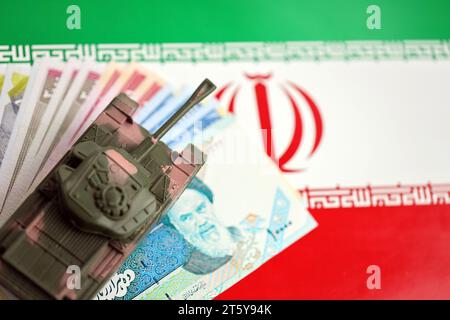 Iranian army toy tank drive on iranian bills of rial currency on flag of Islamic Republic of Iran close up Stock Photo