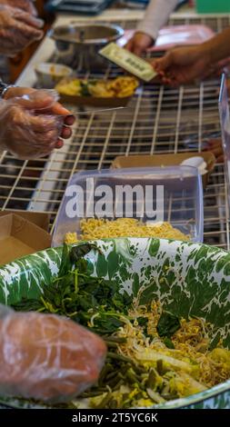 yellow noodles and boiled vegetables such as bean sprouts, spinach, kale, long beans, white mustard greens in a container, are the main ingredients fo Stock Photo