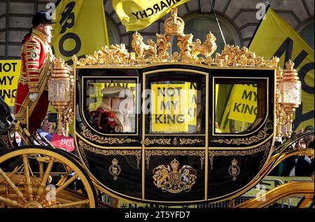 The carriage carrying King Charles III and Queen Camilla passes by protesters from anti-monarchy pressure group Republic as they demonstrate outside the Palace of Westminster in London during the State Opening of Parliament in the House of Lords. Picture date: Tuesday November 7, 2023. Stock Photo