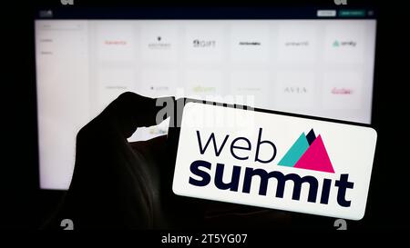 Person holding cellphone with logo of annual technology conference Web Summit (Lisbon) in front of business webpage. Focus on phone display. Stock Photo