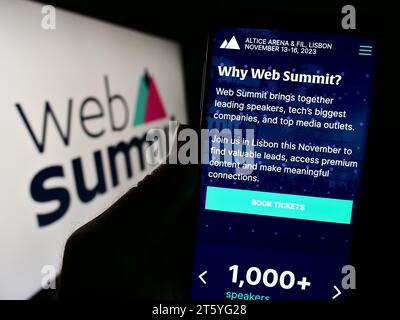 Person holding smartphone with webpage of annual technology conference Web Summit (Lisbon) in front of logo. Focus on center of phone display. Stock Photo