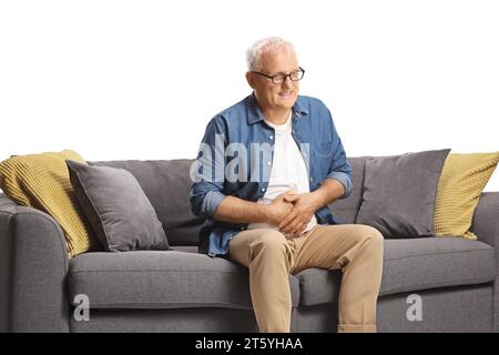 Mature man with abdominal pain sitting on a sofa isolated on white background, health care concept Stock Photo