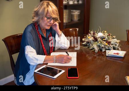 Concentrated older woman sitting in the living room doing sodokus Stock Photo
