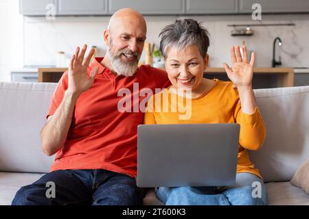 Happy Senior Couple Making Video Call With Laptop At Home Stock Photo