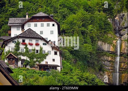 house with flowers and waterfall in Hallstatt village Austria Stock Photo