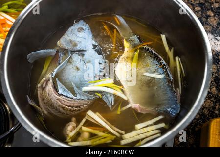 Two carp halves cook in a broth of vinegar, water and vegetables with leek and lemon. The mucus layer on the skin only turns blue when the carp is freshly slaughtered, and the vinegar in the broth stabilises the colour. St. Joseph guest house, Waldsassen Monastery, Waldsassen, Bavaria, Germany. Stock Photo