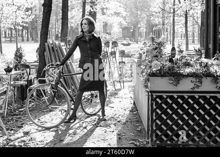 1960s, woman fashion model with bike by kiosk, Jardin des Tuileries garden, Paris, France, Europe, Stock Photo