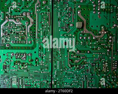 A close-up reveals the intricacies of a green computer circuit board, with various silver and gold components adorning its surface, resembling a techn Stock Photo