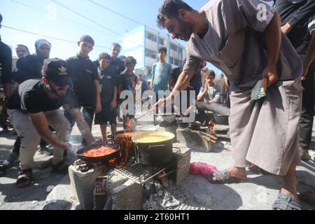 Displaced Palestinians prepare food in front of the United Nations Relief and Works Agency (UNWRA) school at the Nuseirat refugee camp in the central Gaza Strip amid ongoing battles between Israel and the militant group Hamas. Thousands of civilians, both Palestinians and Israelis, have died since October 7, 2023, after Palestinian Hamas militants based in the Gaza Strip entered southern Israel in an unprecedented attack triggering a war declared by Israel on Hamas with retaliatory bombings on Gaza. (Photo by Ahmed Zakot / SOPA Images/Sipa USA) Stock Photo