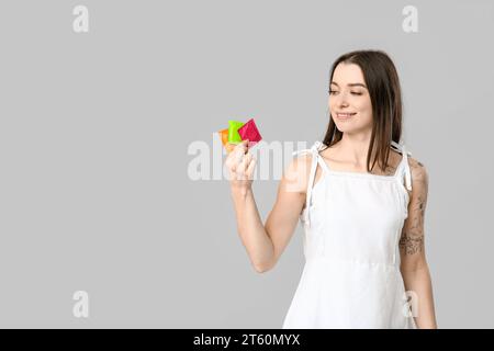 Beautiful young woman with condoms on grey background. AID awareness concept Stock Photo