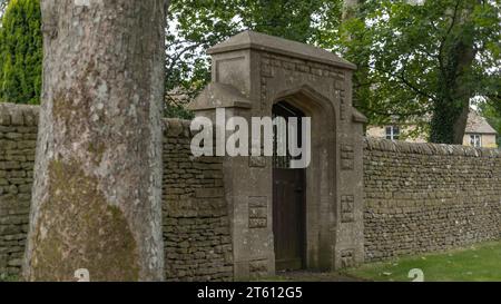 Ancient stone wall and archway carved surround with a wooden gate Stock Photo