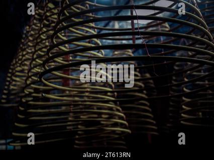 Multiple large yellow incense coils hanging in stacks from the Ceiling in a Chinese shrine. Large Bell Shaped Spiral Incense Coils, Focus and blur. Stock Photo