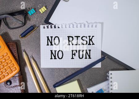 yellow self-adhesive note sticker diagonally on a dark wooden table top with stylized handwriting with the text: no risk no fun. Stock Photo