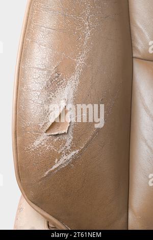 close-up section of used worn and torn leather car seat, beige color seat with wear and tear, including scuffs, creases and scratches, repair Stock Photo