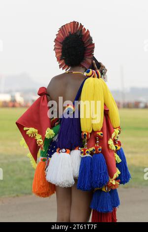 Single young woman talking on mobile phone at Umhlanga reed dance ceremony 2023, Kingdom of Eswatini, traditional dancing clothes, African culture Stock Photo