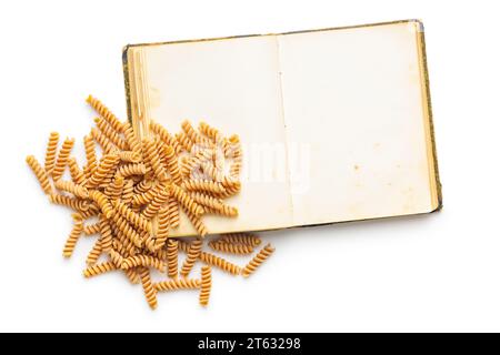Opend blank recipe book and raw whole grain fusilli pasta isolated on the white background. Stock Photo