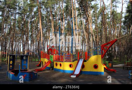 Sandbox, multi-colored slides and swings on the playground for active games in the green area Stock Photo