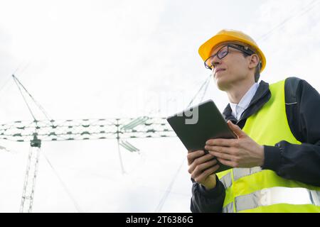 Engineer with digital tablet on a background of power line tower. Stock Photo