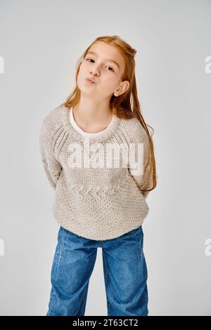 jolly preadolescent girl in knitted trendy sweater looking at camera with pouted lips, fashion Stock Photo