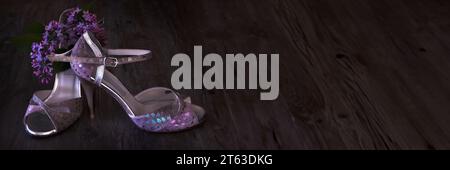 Argentine tango stilettos, dancing shoes and lilac flower on dark wood, panoramic banner image. Stock Photo