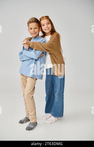 joyous little friends in casual stylish clothes hugging and smiling at camera, fashion concept Stock Photo