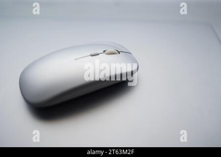 A minimalistic shot of a white computer mouse placed on a blurred smooth gray surface Stock Photo