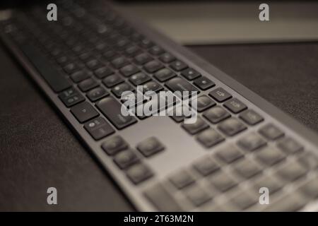 Close-up view of a sleek black computer keyboard with prominent keys showing symbols and numbers on blurred dark surface Stock Photo