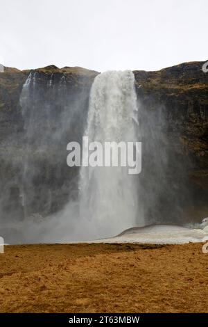 Beautiful view of majestic rapid water falling from rocky cliff against clear sky with landscape in front at Iceland Stock Photo