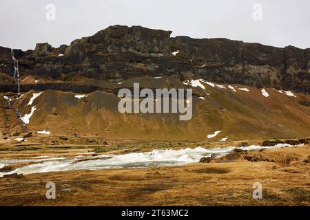 Picturesque view of scenic river flowing by majestic rocky mountain range during winter in Iceland Stock Photo