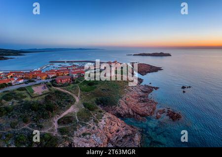 From above drone view of Castelsardo village with its historic tower, marina, and surrounding coastline during sunset in Sardinia, Italy Stock Photo