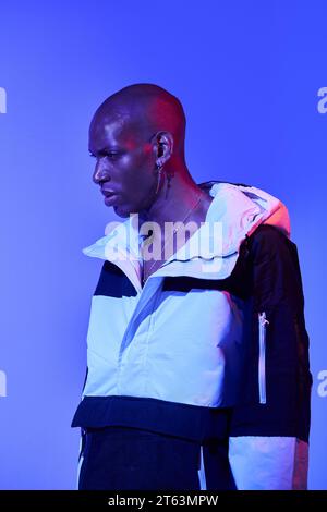 Side view of stylish confident bald young man in casual outfit looking away and posing on blue background Stock Photo